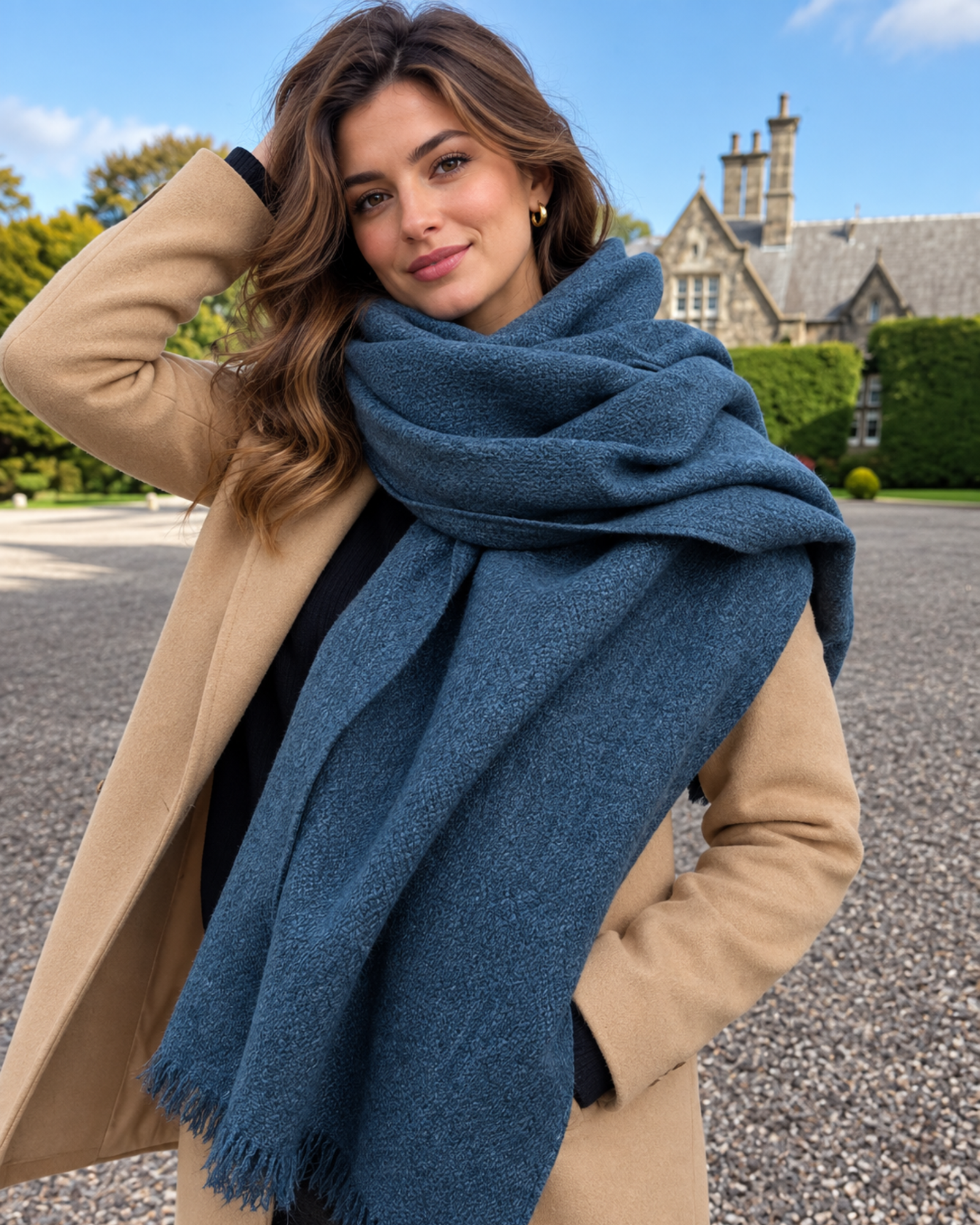 1 Woman wearing a blue tweed-style wool shawl with frayed fringe over a camel coat outdoors