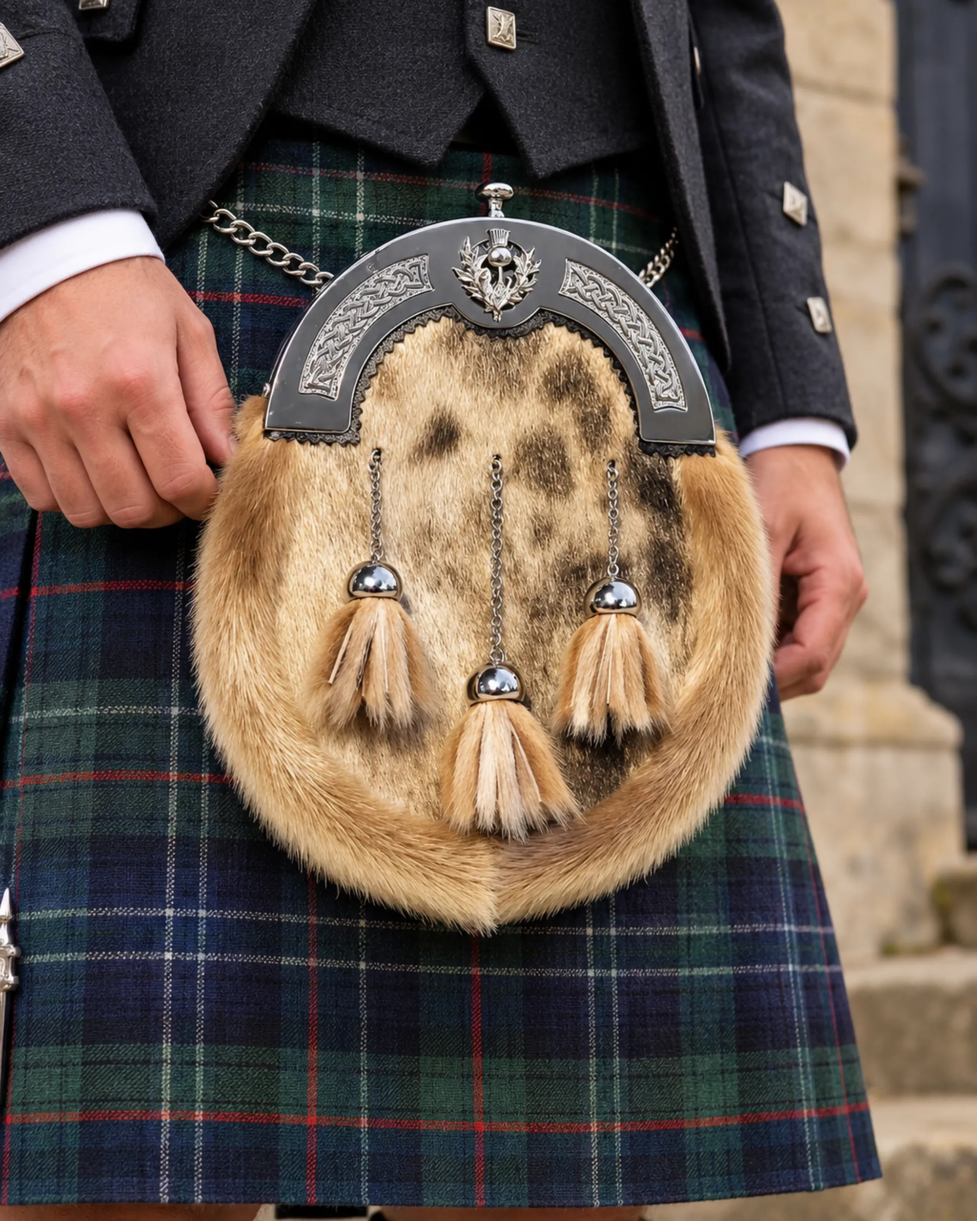 1 Full fur dress sporran with an engraved pewter cantle featuring Celtic knotwork and a thistle motif, worn against a navy and green tartan kilt.