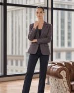 Woman wearing a plum tweed blazer with herringbone-style texture, notch lapels, and tailored silhouette, styled with black trousers and a black top.
