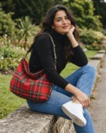 Red tartan hobo shoulder bag with black and leopard print strap and brass fittings on a white background